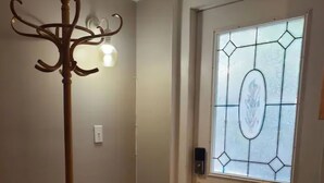 Et værelse med et træklædeskab, en dør med farvet glas, en stol og et lille bord.