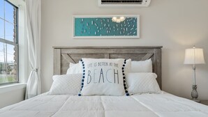 Un lit bien fait, avec une literie blanche et deux oreillers, dont l’un porte un motif textuel.