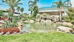 Un jardin aménagé avec un bassin, des palmiers et une cascade.