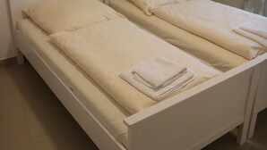 A double bed with white bedding and a small bedside table. - Penthaus Am Köpcke (Hannover)