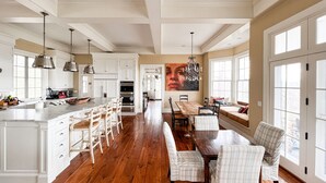 A spacious kitchen with a large island, wooden flooring, and white cabinetry. - Chef’s Kitchen, Fast Wi-Fi (Hillsdale)