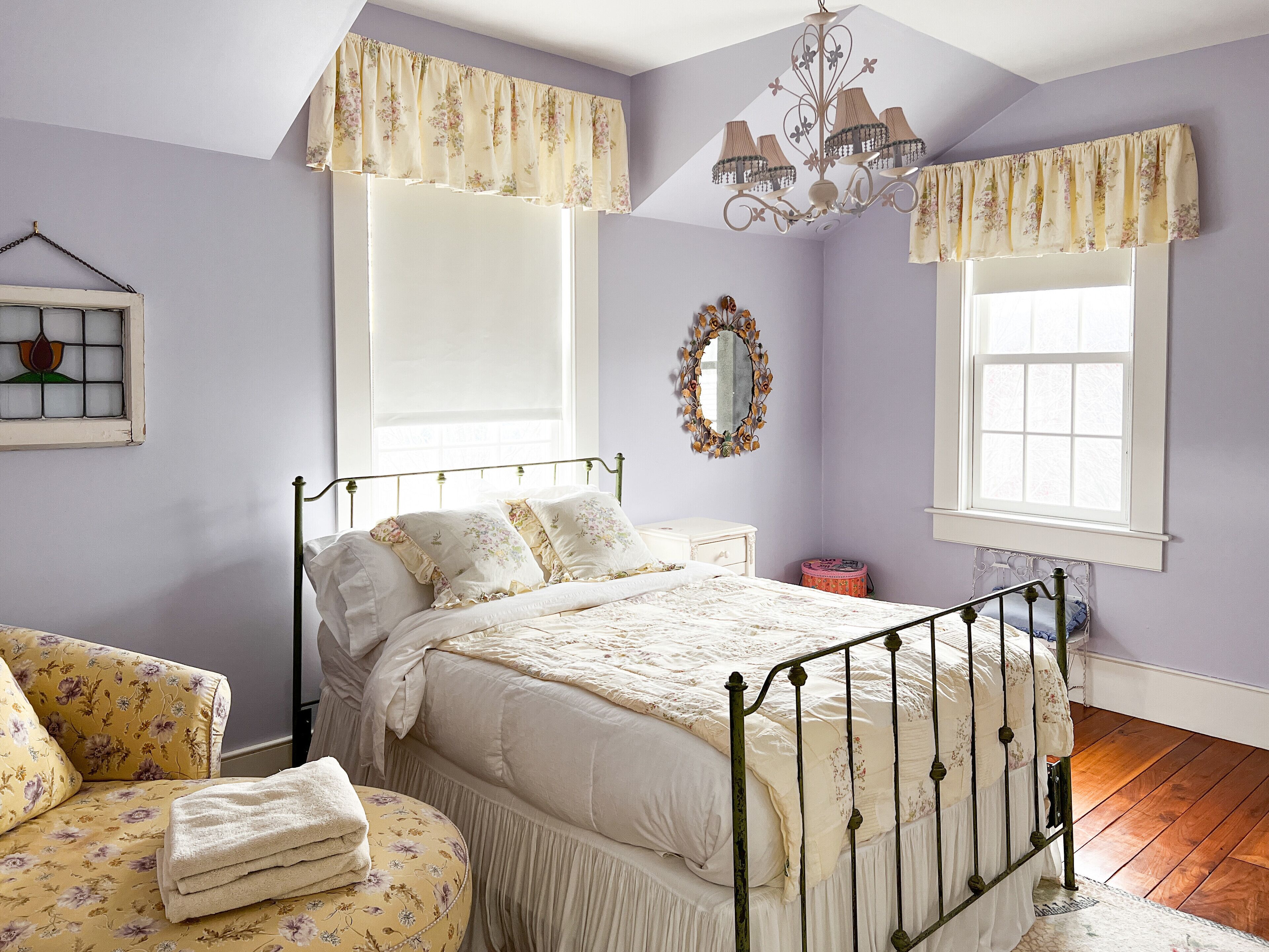 Une chambre à coucher comprenant un lit, une chaise, une commode, un miroir et un lustre.