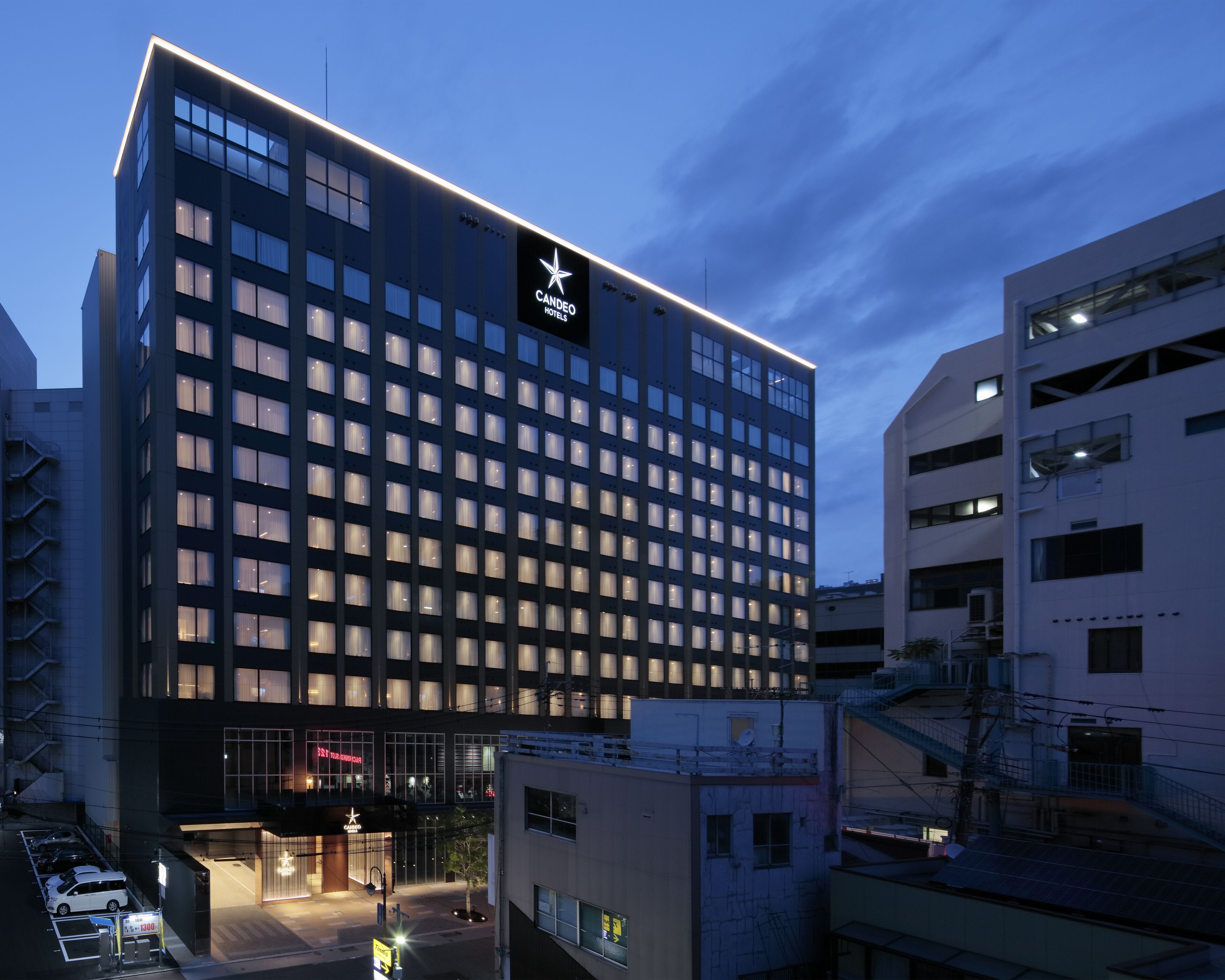 A modern hotel building with a prominent star logo, multiple floors, and a well-lit entrance.