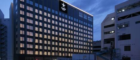 Un hotel moderno con un logotipo de estrella destacado, varios pisos y una entrada bien iluminada.