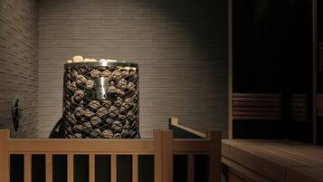 Una sauna con un banco de madera, pared de piedra y una lámpara colgante.