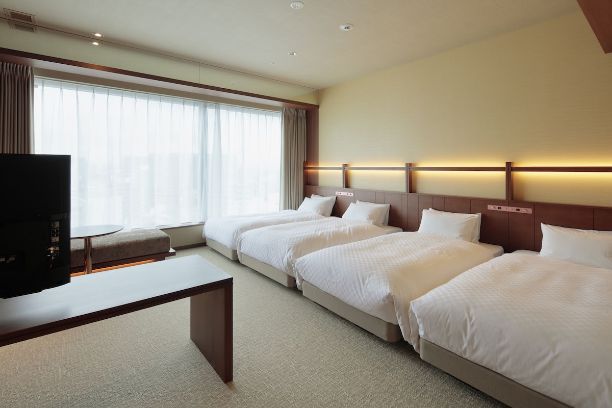 A hotel room with two beds, a TV, and a desk.