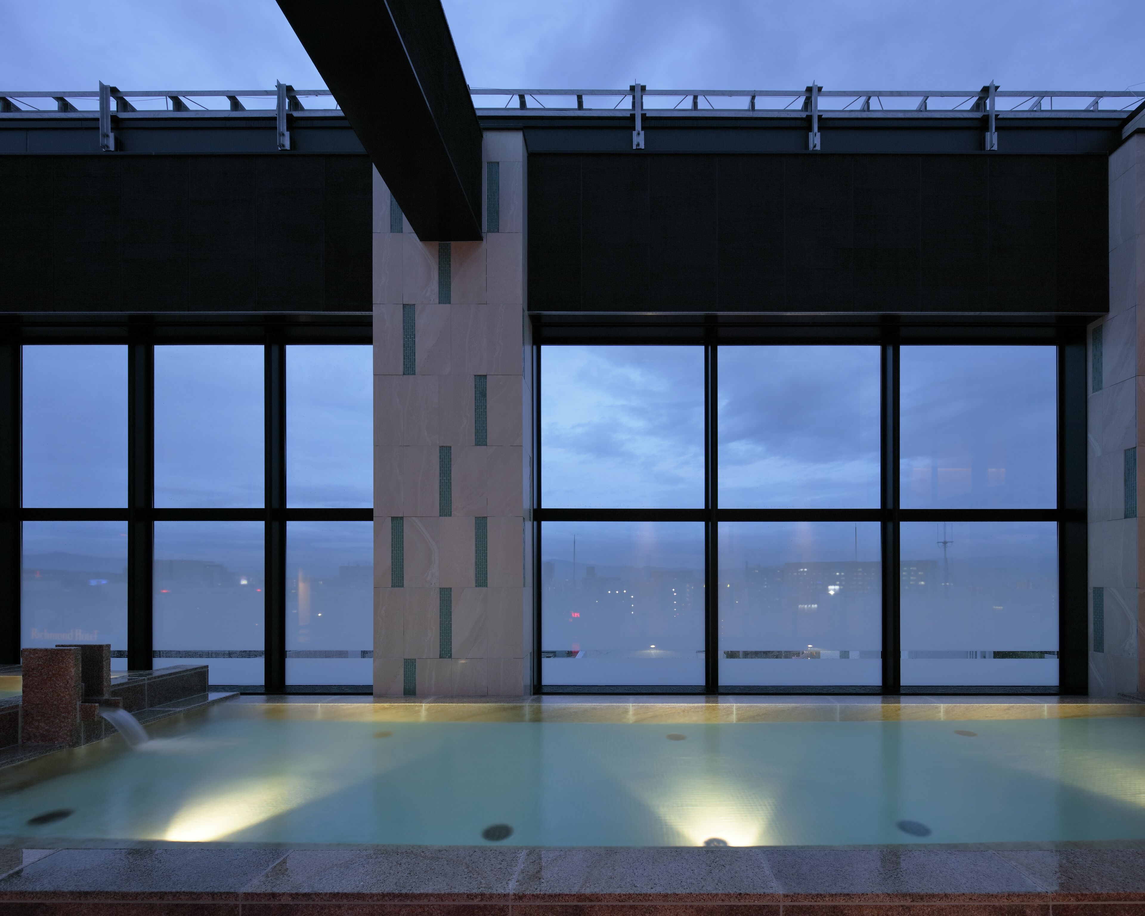A modern indoor pool with large windows offering a city view.