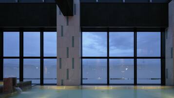 A modern indoor pool with large windows offering a city view.