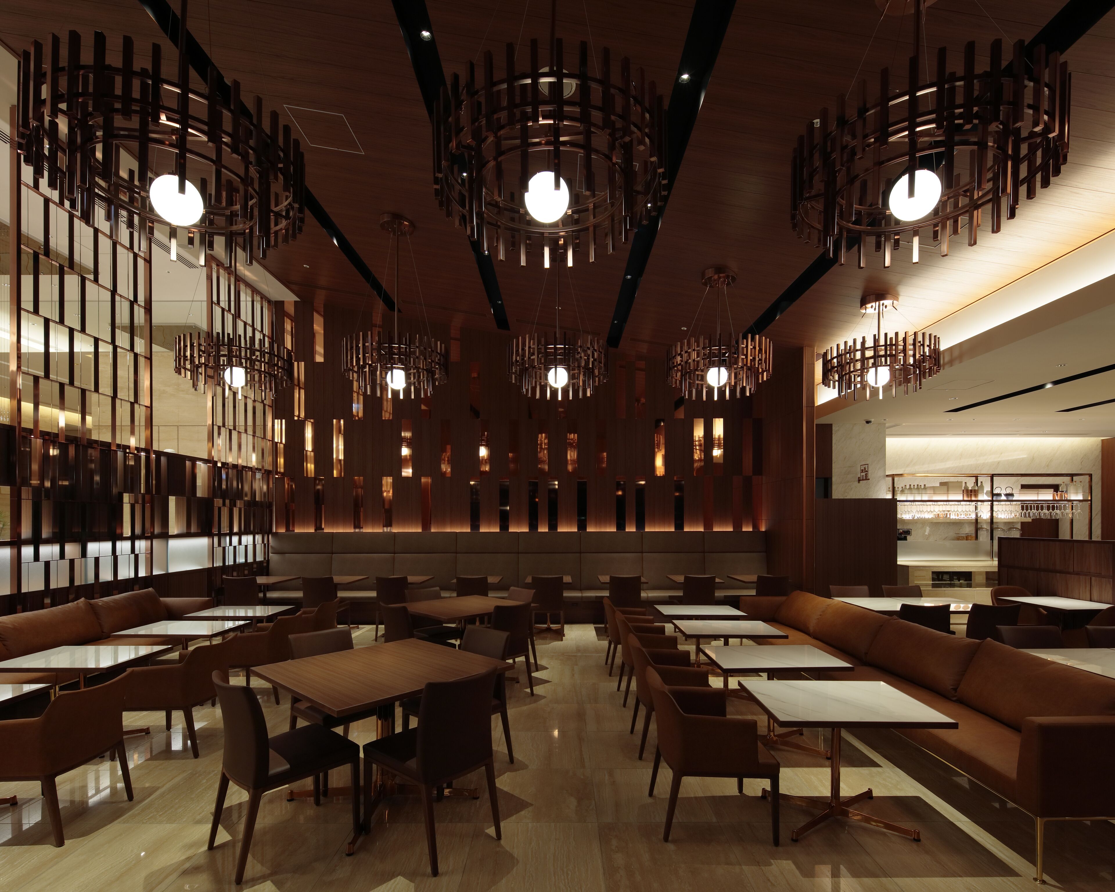 A modern restaurant with high ceilings, pendant lighting, and a mix of seating arrangements including tables and sofas.