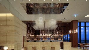A modern hotel lobby with a reception desk, seating area, and large windows offering a city view. - Candeo Hotels Kumamoto Shinshigai (Kumamoto)