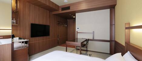 Une chambre d’hôtel équipée d’un lit, d’une télévision, d’un bureau et d’une armoire.