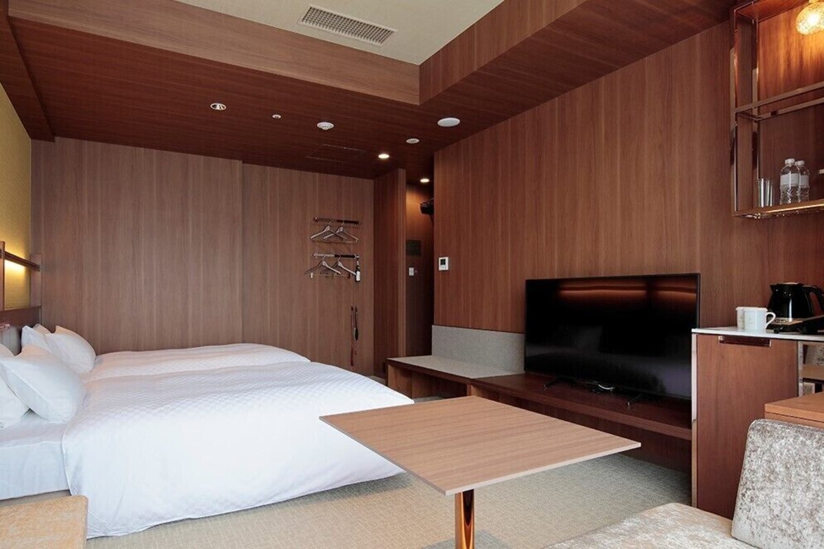 Een hotelkamer met een bed, een televisie, een koffiezetapparaat en een tv-meubel.