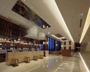 Un hall d’hôtel moderne avec un comptoir d’accueil, un espace salon et de grandes fenêtres.