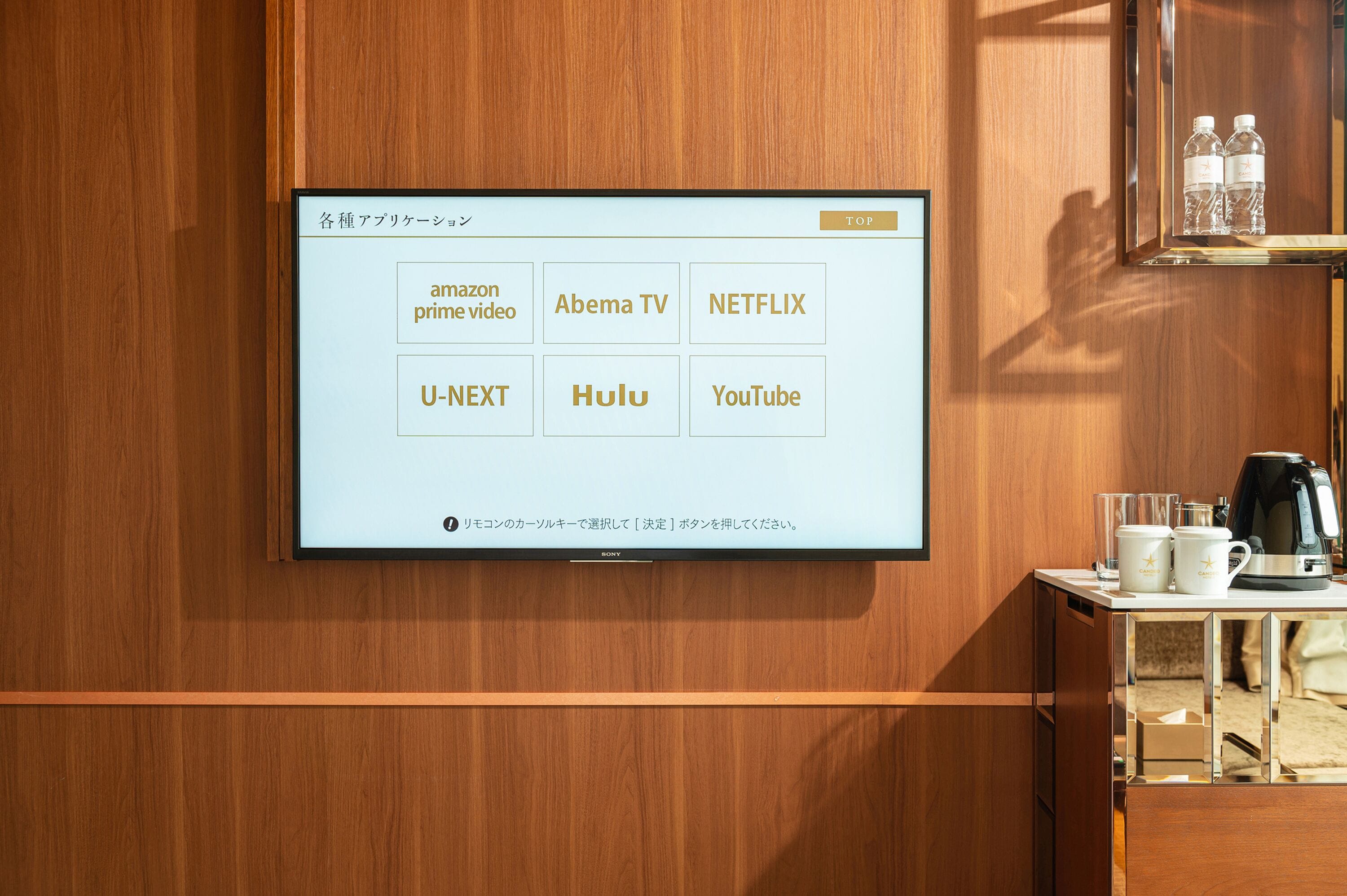 A wall-mounted TV displaying a selection of streaming services.