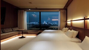 A hotel room with a large bed, a seating area, and a view of the cityscape. - Candeo Hotels Kumamoto Shinshigai (Kumamoto)