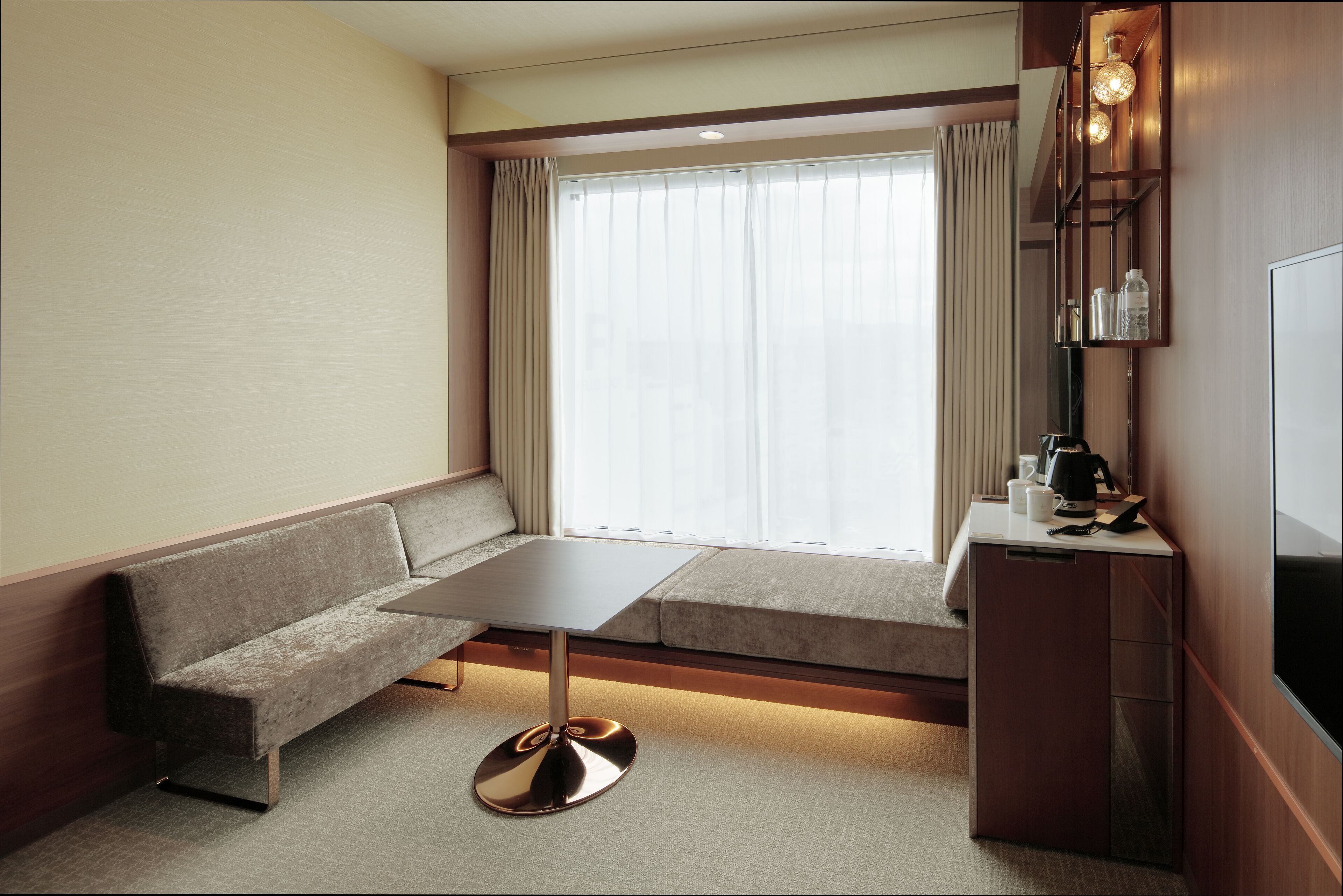 Et moderne hotelværelse med sofa, lille bord, fjernsyn og minibar.