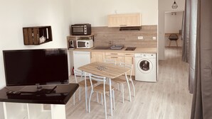 A modern kitchen with a dining area, a washing machine, and a TV.