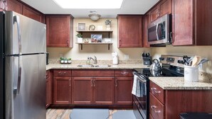 Une cuisine moderne avec des meubles en bois, des appareils en acier inoxydable et un plan de travail en granit.