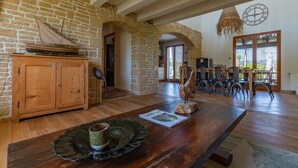A spacious room with a wooden table, a ship model, and a stone wall.