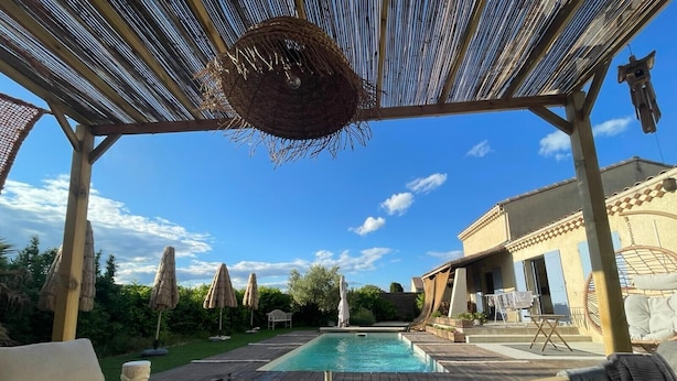 A poolside area with a pergola, outdoor furniture, and a dining table set for a meal.