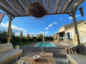 A poolside area with a pergola, outdoor furniture, and a dining table set for a meal. - Holiday Home with Private Pool for Large Families, No Overlooking Neighbors (Montélimar)