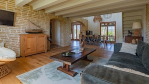 A spacious living area with a stone wall, wooden furniture, and a large window.