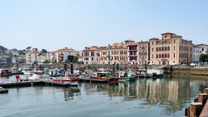 Un port de plaisance avec des bateaux amarrés, un bâtiment situé au bord de l’eau et un ciel dégagé.