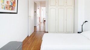 Une chambre à coucher comprenant un lit, une armoire, un banc et une œuvre d’art encadrée accrochée au mur.