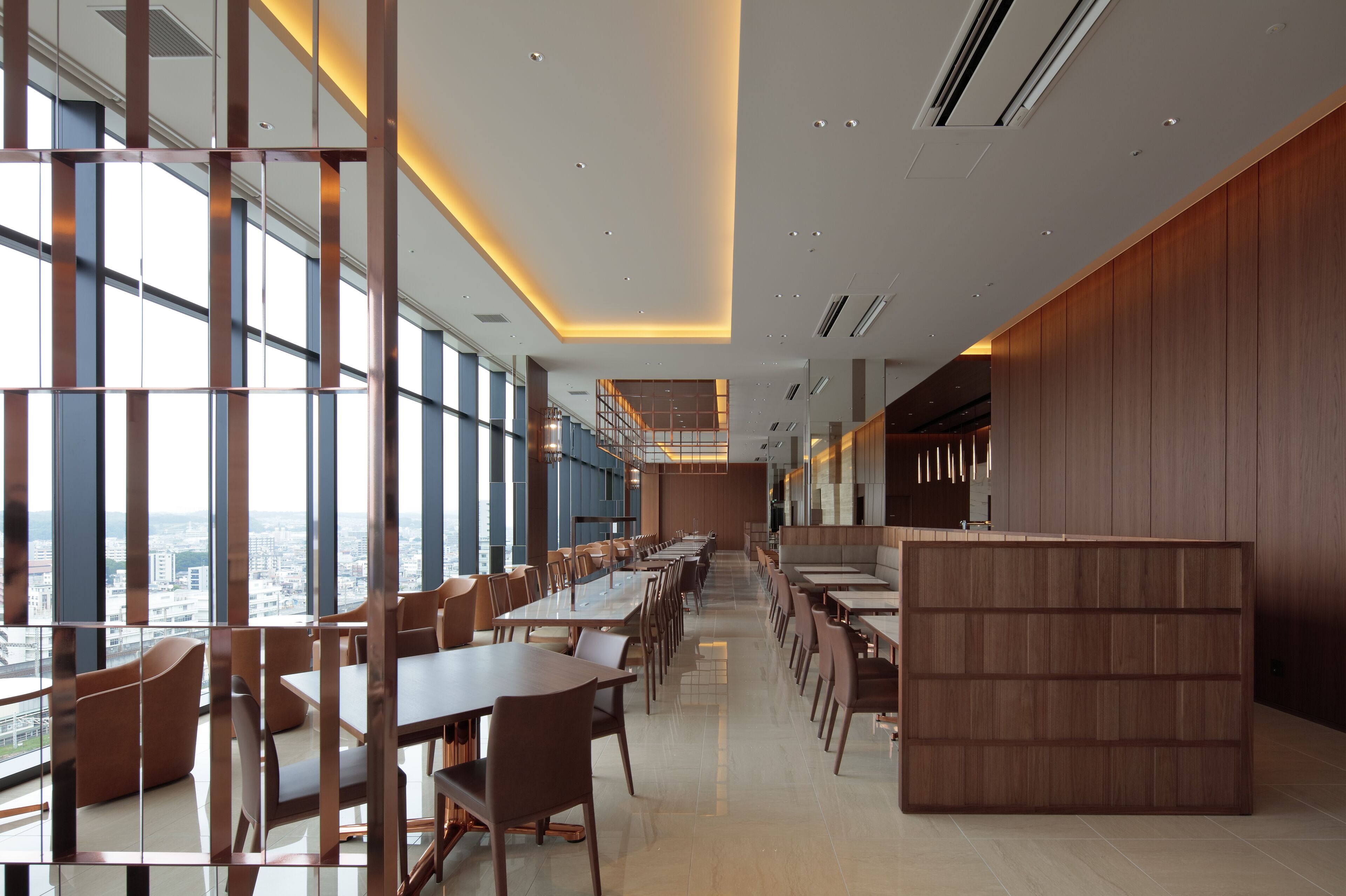 A modern dining area with high ceilings, large windows, and a central bar area.