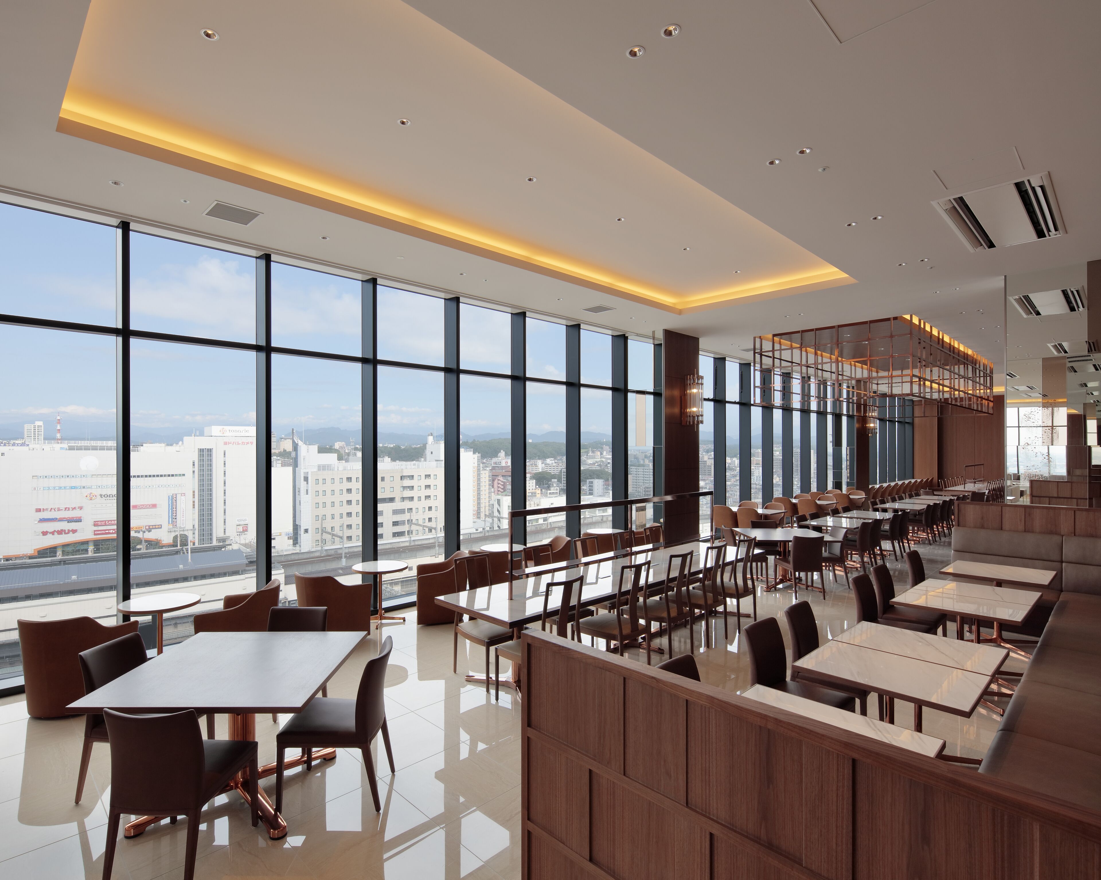 A modern dining area with large windows, high ceilings, and a city view.