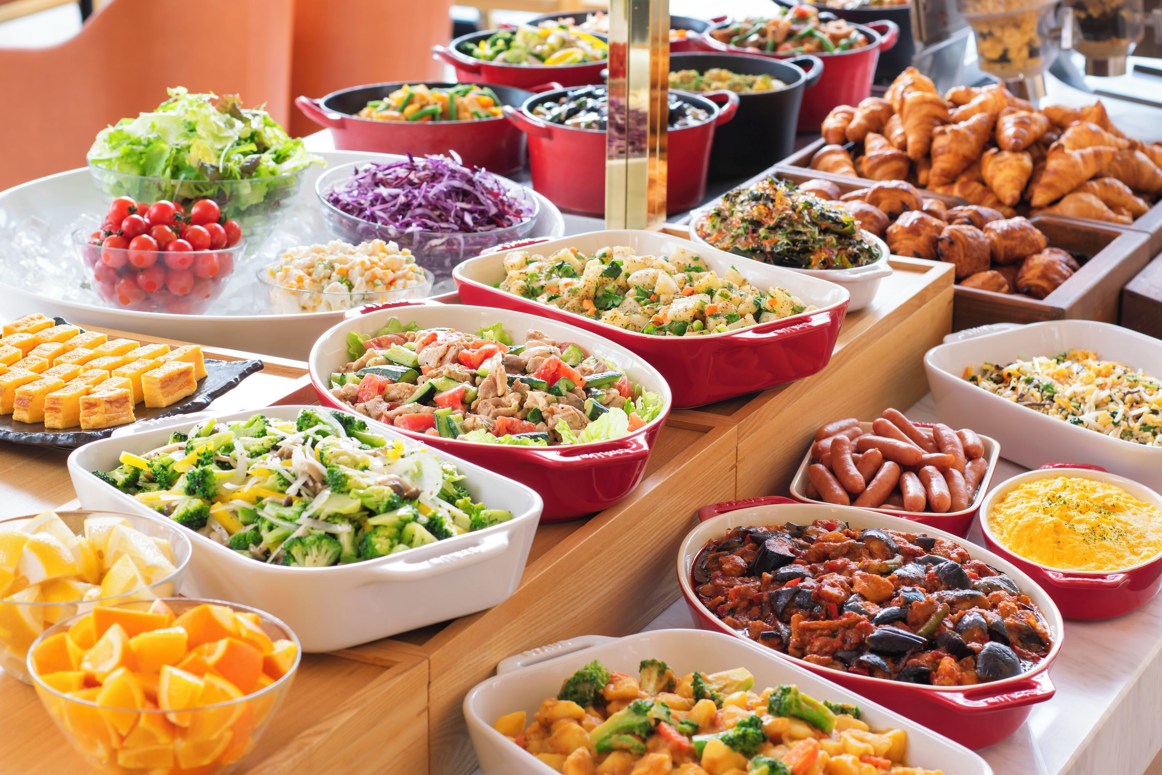 A buffet table with various dishes including salads, vegetables, and baked goods.