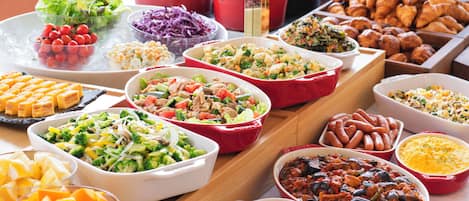 A buffet table with various dishes including salads, vegetables, and baked goods.