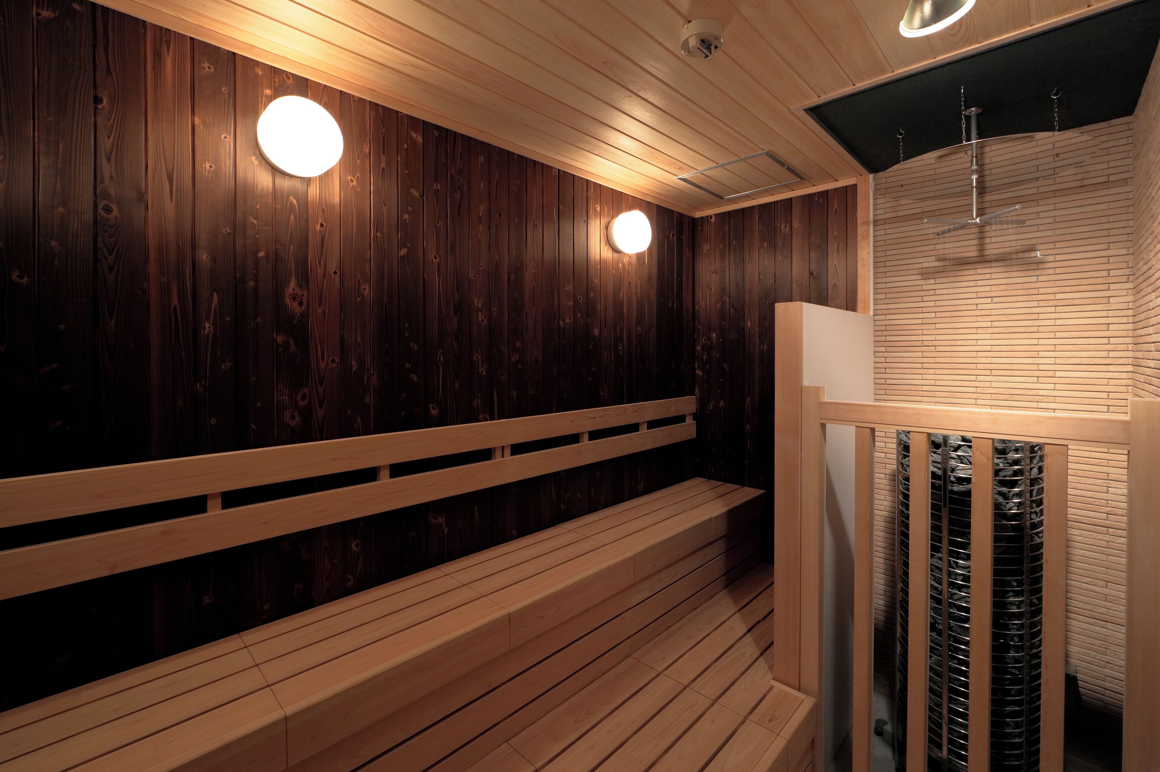 A wooden sauna with benches and a ceiling fan.