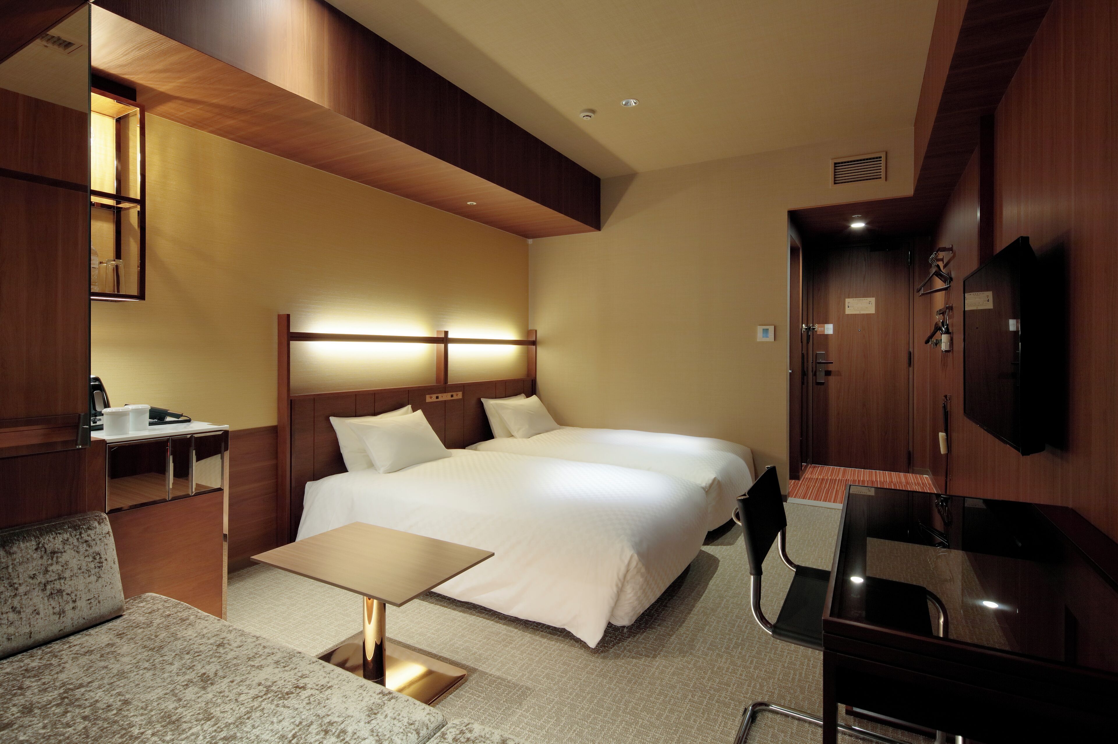 A hotel room with a large bed, a desk, a chair, a TV, and a mirror.