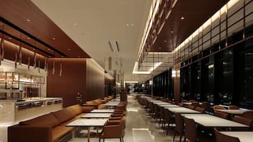 A modern restaurant with a long counter, cushioned seating, and a city view.