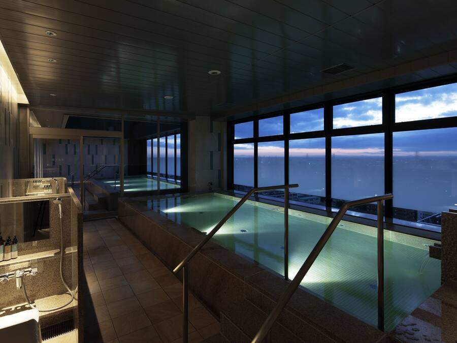 A modern indoor pool with a glass barrier, a sauna area, and a view of the ocean.