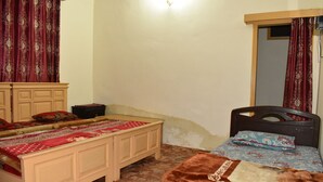 A bedroom with two beds, a wooden headboard, a nightstand, a dresser, and a mirror. - Snow Land Hotel Kaghan (Balakot)