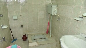 A bathroom with a toilet, bidet, sink, and a mop. - Snow Land Hotel Kaghan (Balakot)