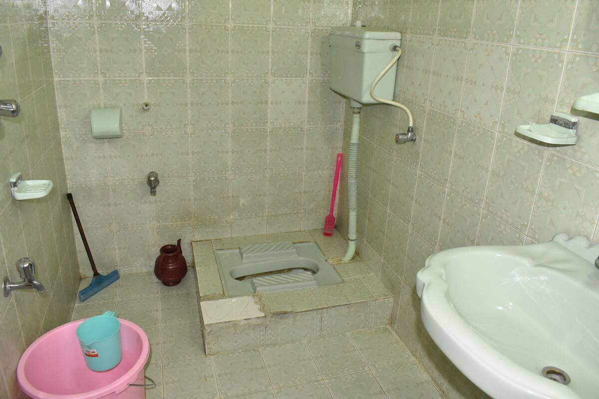 A bathroom with a toilet, bidet, sink, and a mop.