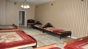 A hotel room with four single beds, a chandelier, striped wallpaper, and a tiled floor. - Snow Land Hotel Kaghan (Balakot)
