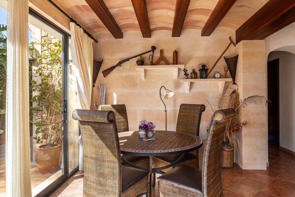Un coin repas avec des chaises en osier, une table ronde et une plante en pot.