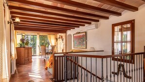 Una habitación amplia con techo de madera, una escalera con barandilla y vistas al exterior.