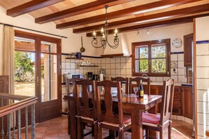 Un espace repas avec des chaises en bois, un lustre et une vue sur l’extérieur.
