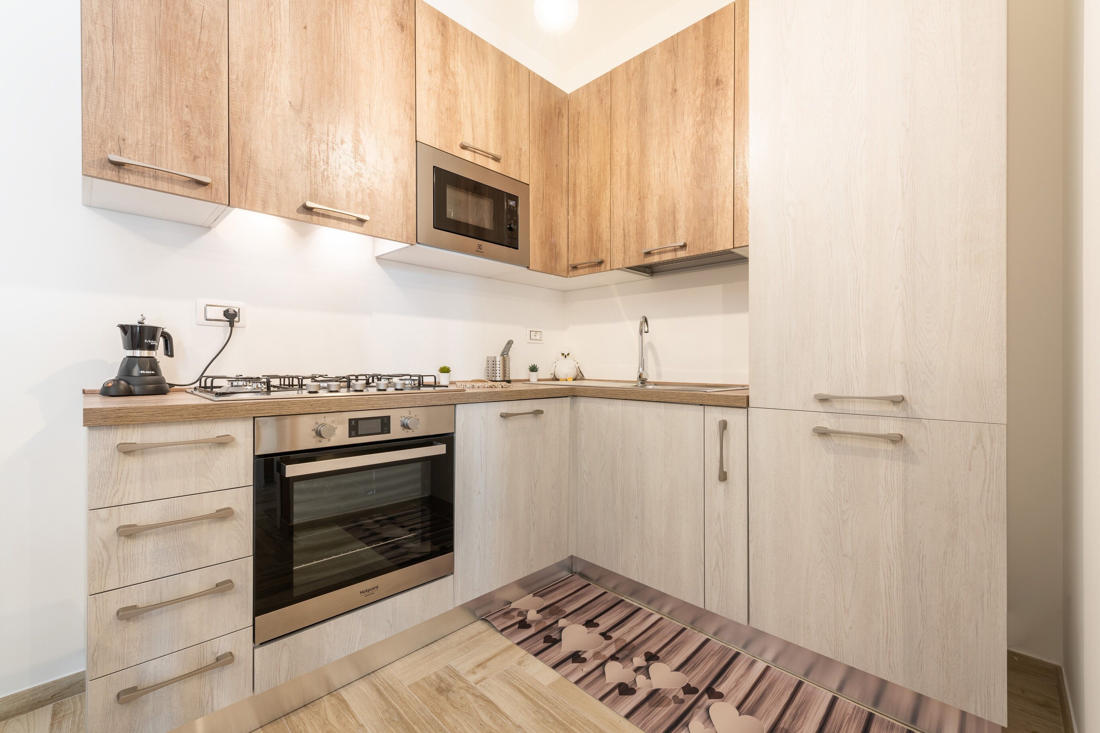 Une cuisine moderne avec des meubles en bois, un four à micro-ondes encastré, une cuisinière et une machine à café.