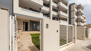 A multi-story residential building with balconies, a gated entrance, and a paved driveway. - Holiday Home Casa Mattia with Terraces, Garden & Wi-Fi (Quartu Sant'Elena)