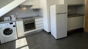 Cocina compacta con lavadora, horno y refrigerador.