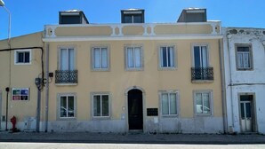 Un edificio de varios pisos con entrada central, balcones y un hidrante cercano.