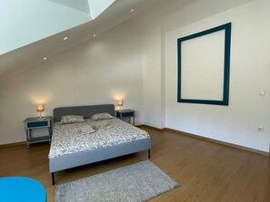 A modern bedroom with a large bed, two bedside tables, and a large framed picture on the wall.