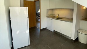 Una cocina compacta con un refrigerador blanco, salpicadero de azulejos y un lavamanos pequeño.