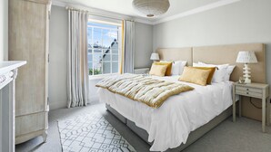Un dormitorio con una cama grande, una mesita de noche con lámparas, un armario y vistas al exterior.